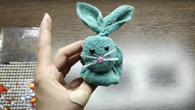 A woman holds a rabbit she made by folding a microfiber cloth and adding some facial features