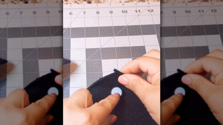 A woman holds a magnet in the corner of an old microfiber cloth