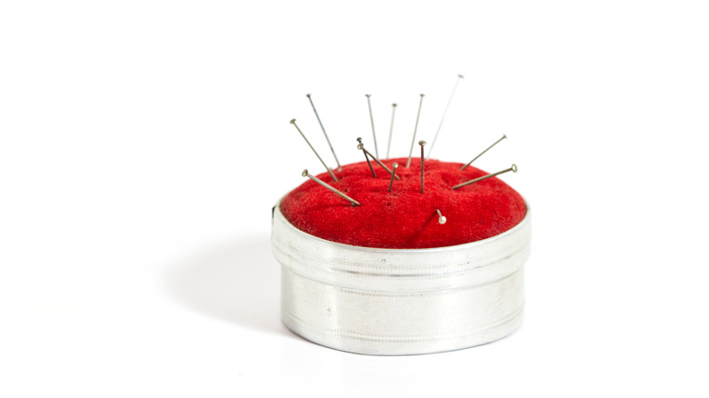 A pin cushion with a metal ring and red fabric.