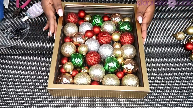 Shadow box filled with various ornaments of red, green, silver, and gold