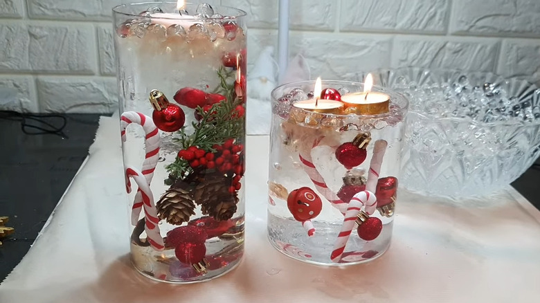 Two water-filled vases with ornaments and decorations topped by a lit tealight