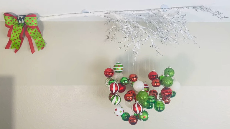 Green and red dotted bow on a silver branch hung with green, red, and white ornaments in various patterns