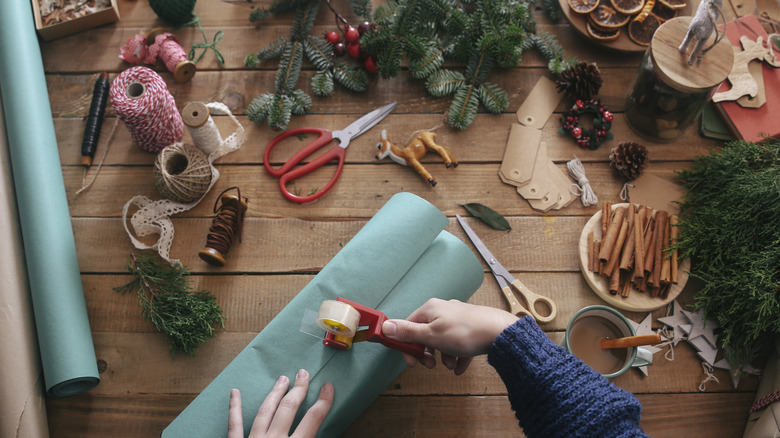 Woman taping present with ornaments on table