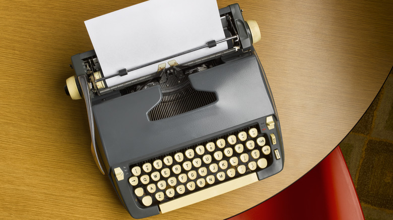 An old typewriter with blank page inserted in it on a wood table