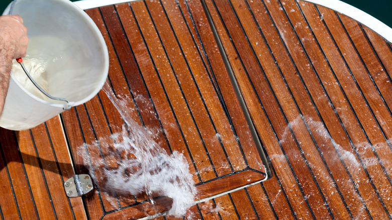 Man rinses wooden deck