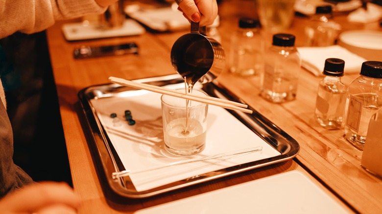 woman pouring hot wax into a container