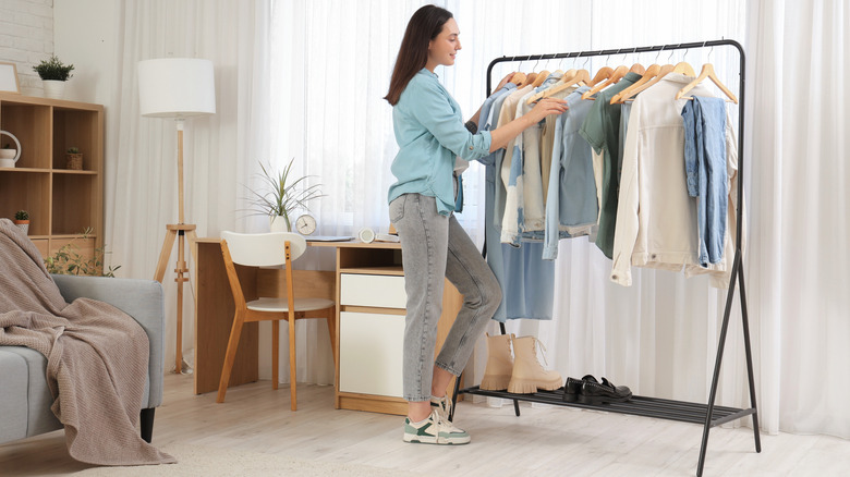 woman searching clothing rack in bedroom