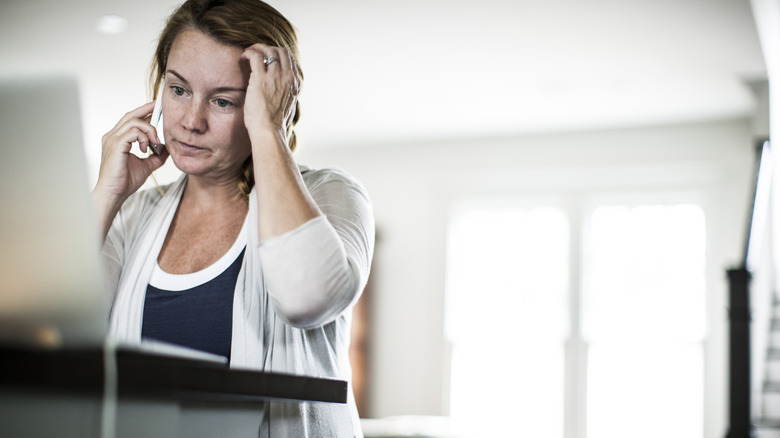 A frustrated woman holds her head while on the phone