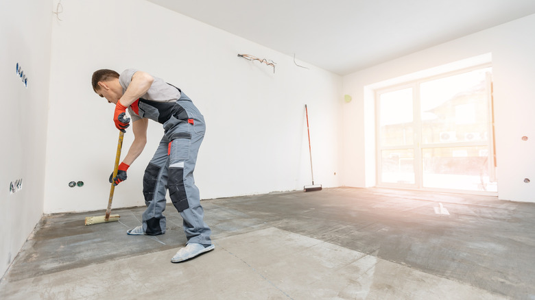 Man using roller on concrete floor indoors