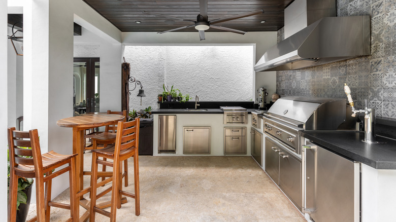 Outdoor kitchen with stainless steel appliances and wood chairs