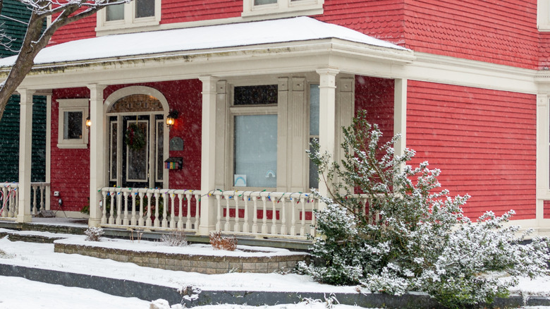 Snow on the veranda and exterior of a red home