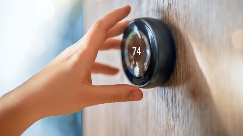 Hand reaching for smart thermostat