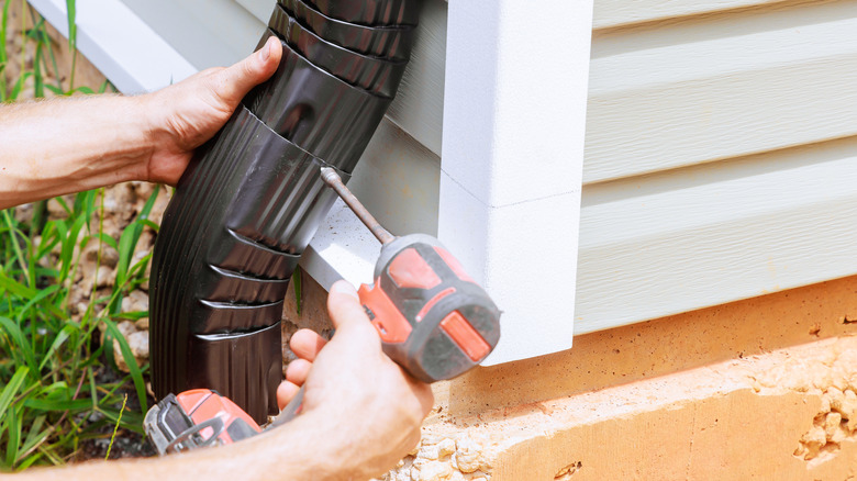 Person attaching a downspout extension