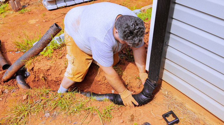 Person installing an underground downspout extension