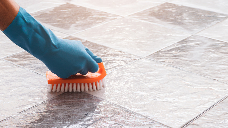 Hand scrubbing tile floors with gloves on