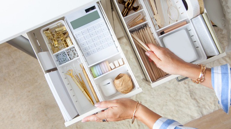 Woman opening organized desk drawers