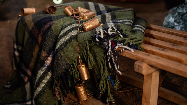 String of rustic bells and a plaid blanket draped over wood bench