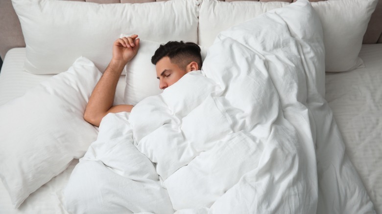 Man under white down duvet 