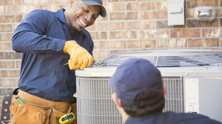 men checking outdoor air con unit