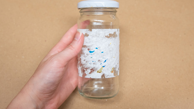 hand holding jar with label residue