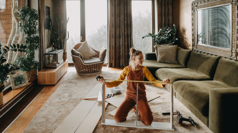 Young woman assembling a furniture piece on her living room floor