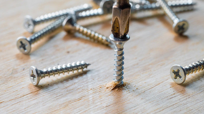 Screw being inserted into wood plank with other screws around