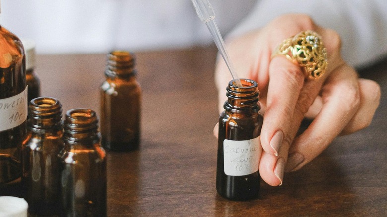 Woman adding drops of essential oil to bottle