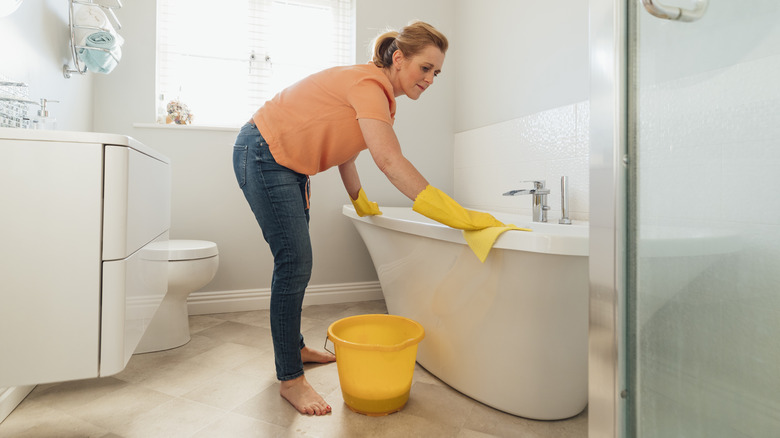 Woman cleaning white bathtub