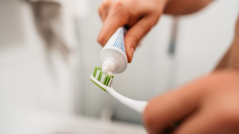 person putting toothpaste on toothbrush