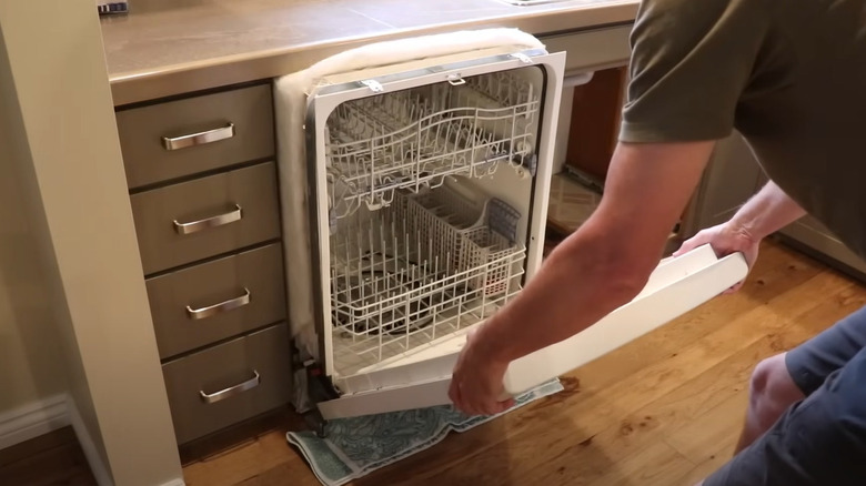 man sliding dishwasher out
