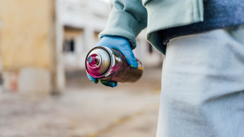 holding can of spray paint with pink paint