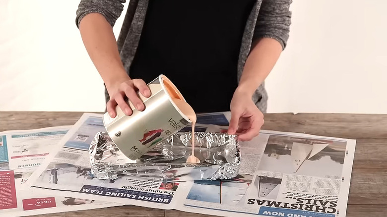 Person pouring paint into a foil-lined paint tray