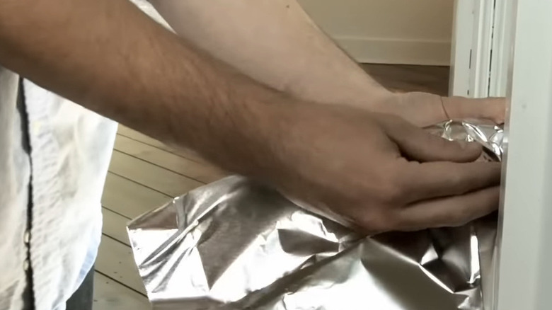 Hands wrapping foil around a doorknob