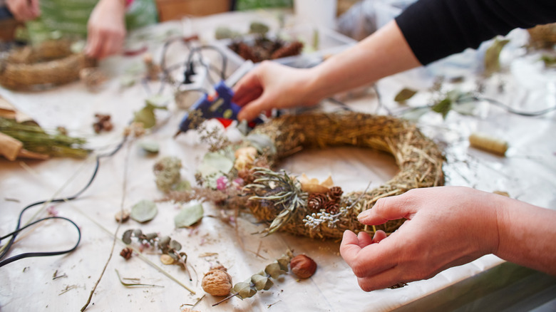 hands decorating straw wreath 