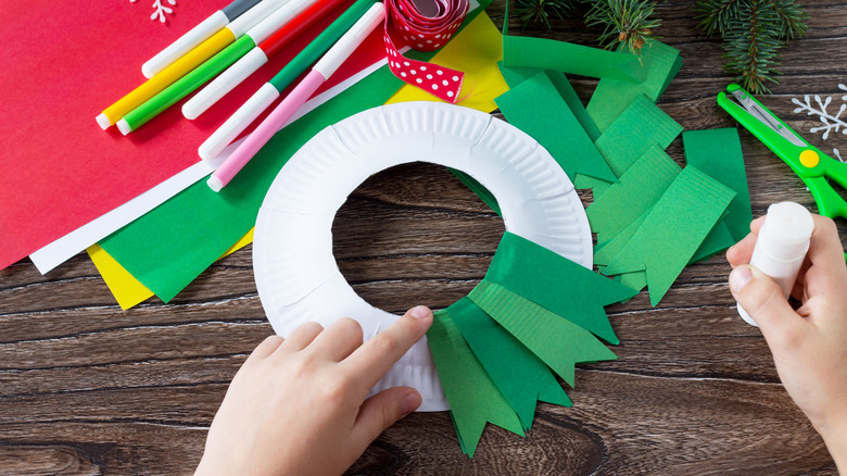 child's hands crafting paper wreath