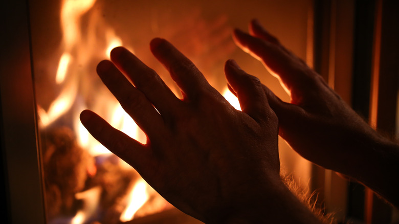 hands hovering by fireplace