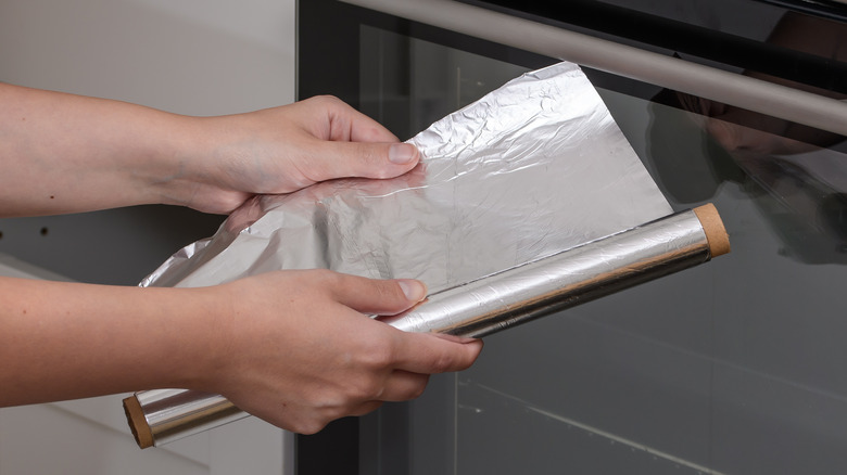 hands unrolling aluminum foil