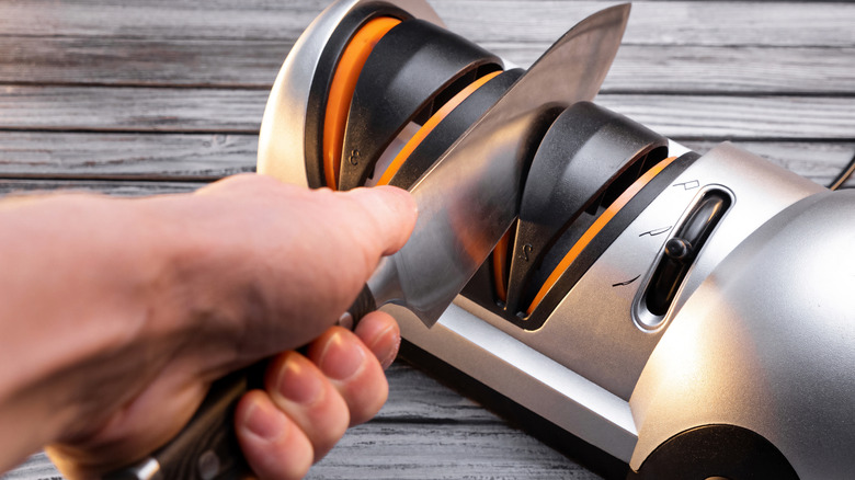 A person uses a knife sharpener