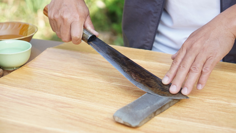 A person sharpens a knife using a whetstone