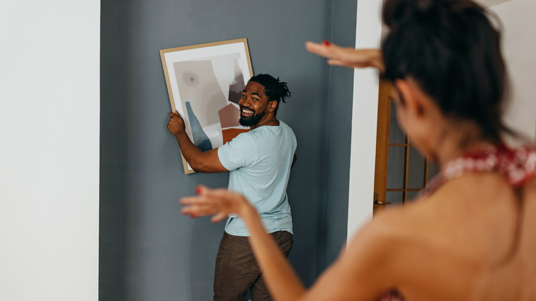 couple mounting artwork on wall