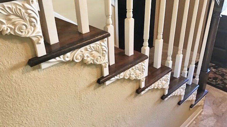 A dark stained wooden staircase with white stair brackets