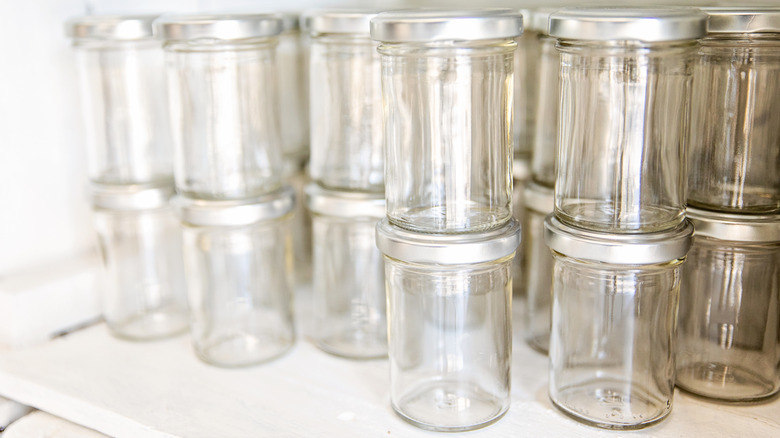 Stacks of empty lidded glass jars sit on a shelf