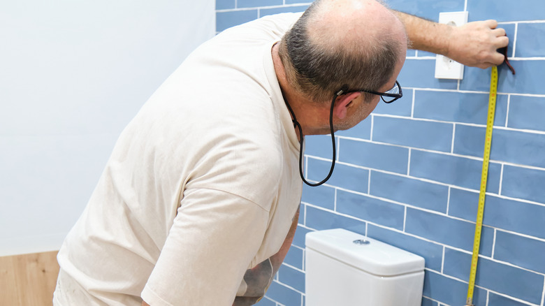 person measuring the bathroom dimensions