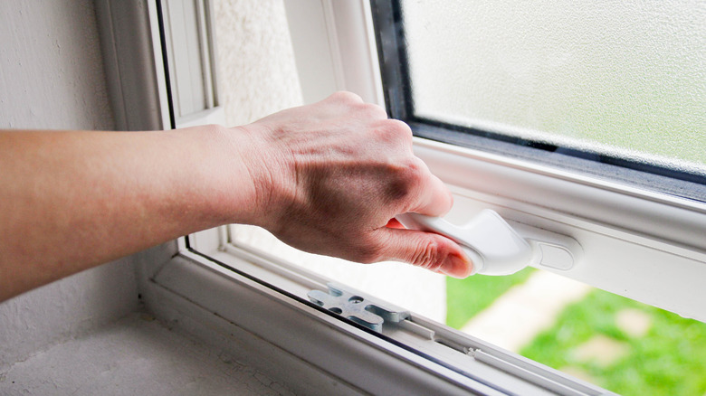 Close-up of person's hands opening window