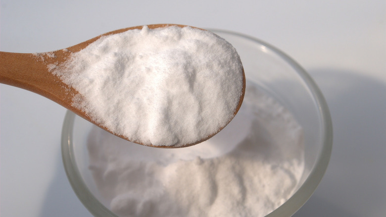 baking soda on a wooden spoon held above a glass bowl