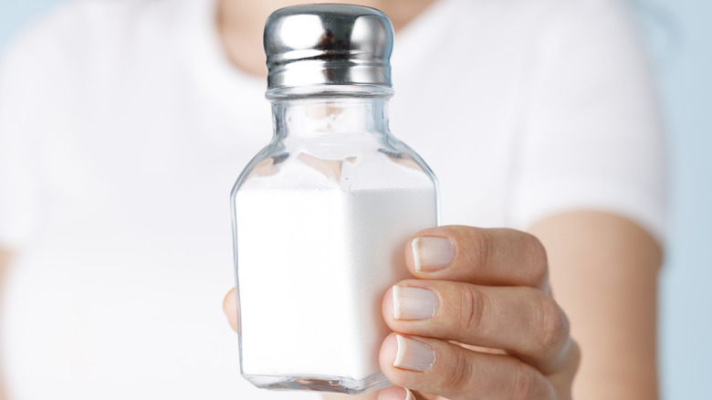 Woman holding out salt shaker