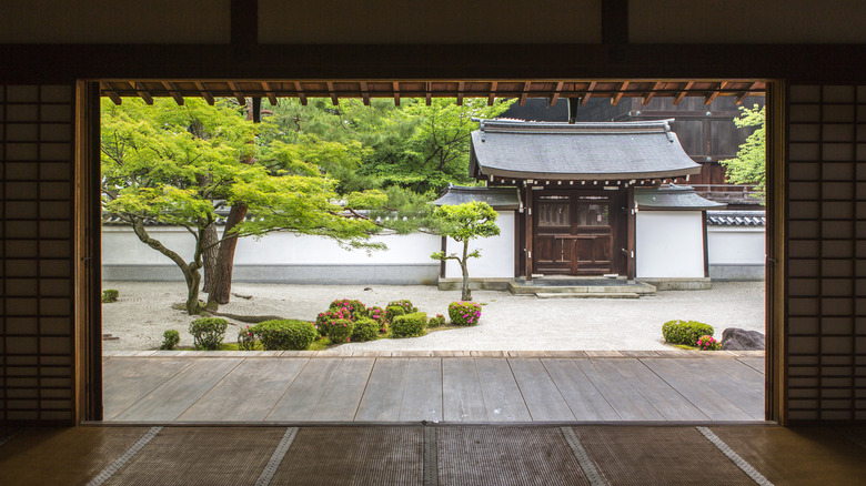 A large doorway framing a minimalistic Japanese garden with raked gravel and plants