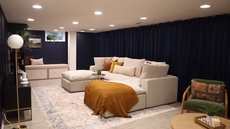 Basement with blue curtains and floor lamp next to media console