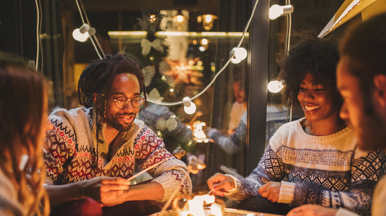 A group of friends make s'more on a patio