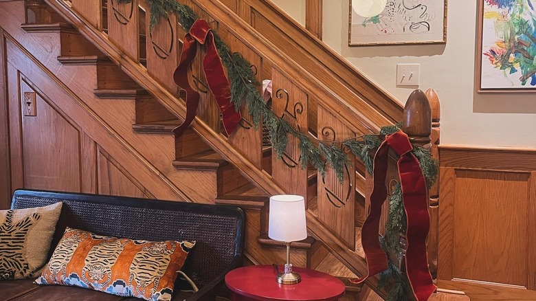 Green garland with red bows on wooden bannister